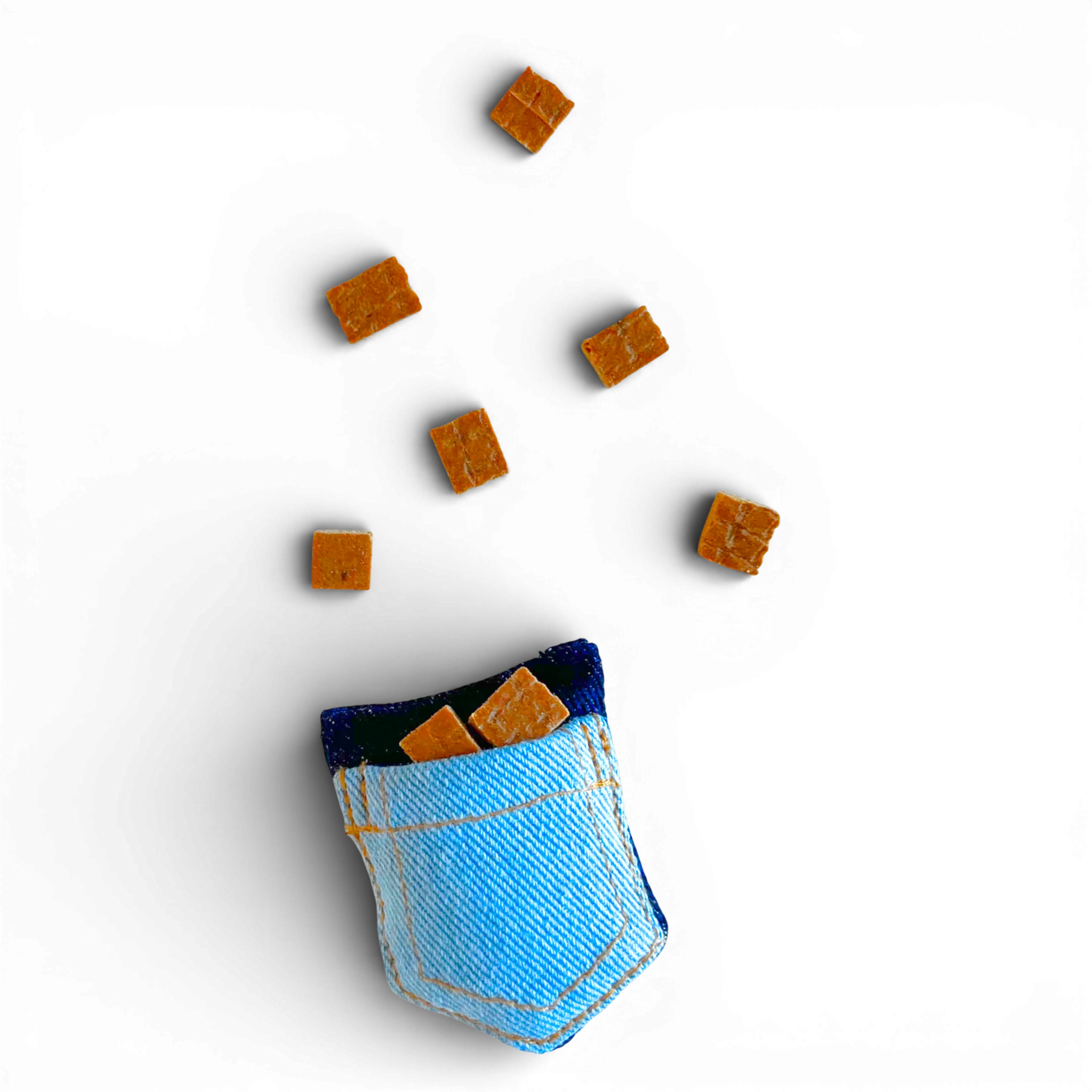 Small denim pocket cat toy next to scattered catnip treats on a light background.