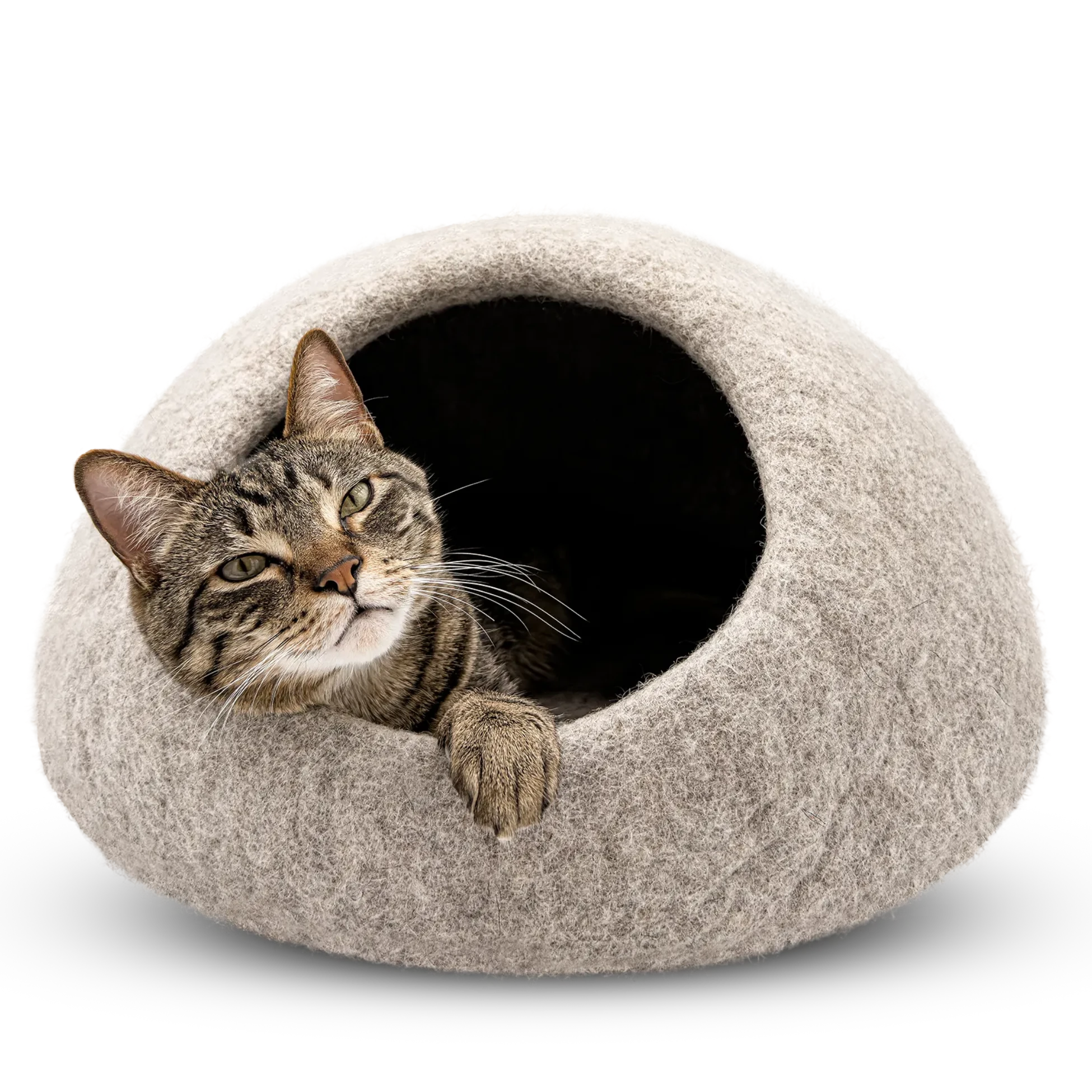 Tabby cat resting at the opening of a light brown felted wool cat cave bed on a white background