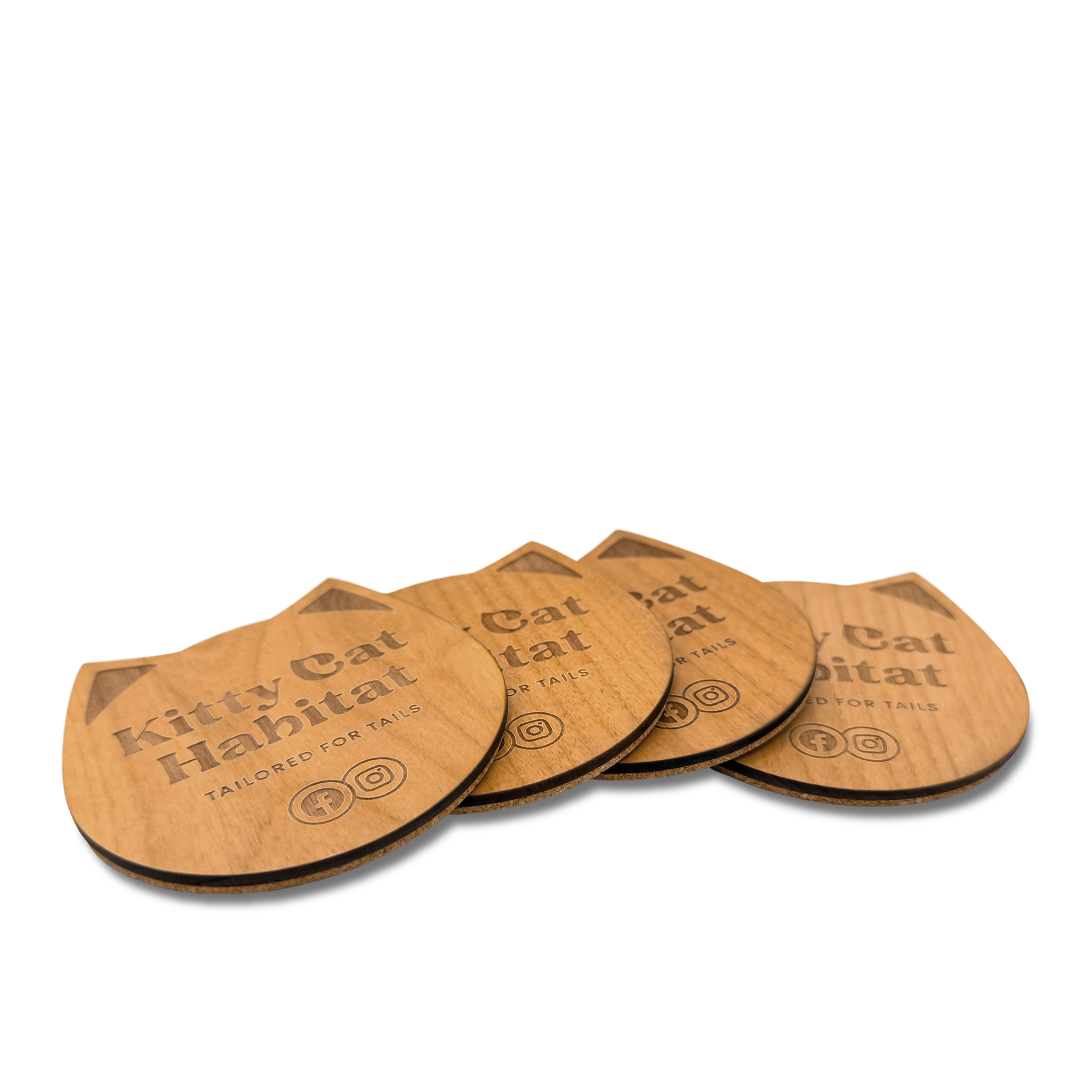 Group of wooden cat head drink coasters fanned out to show the engraved design on a light background.