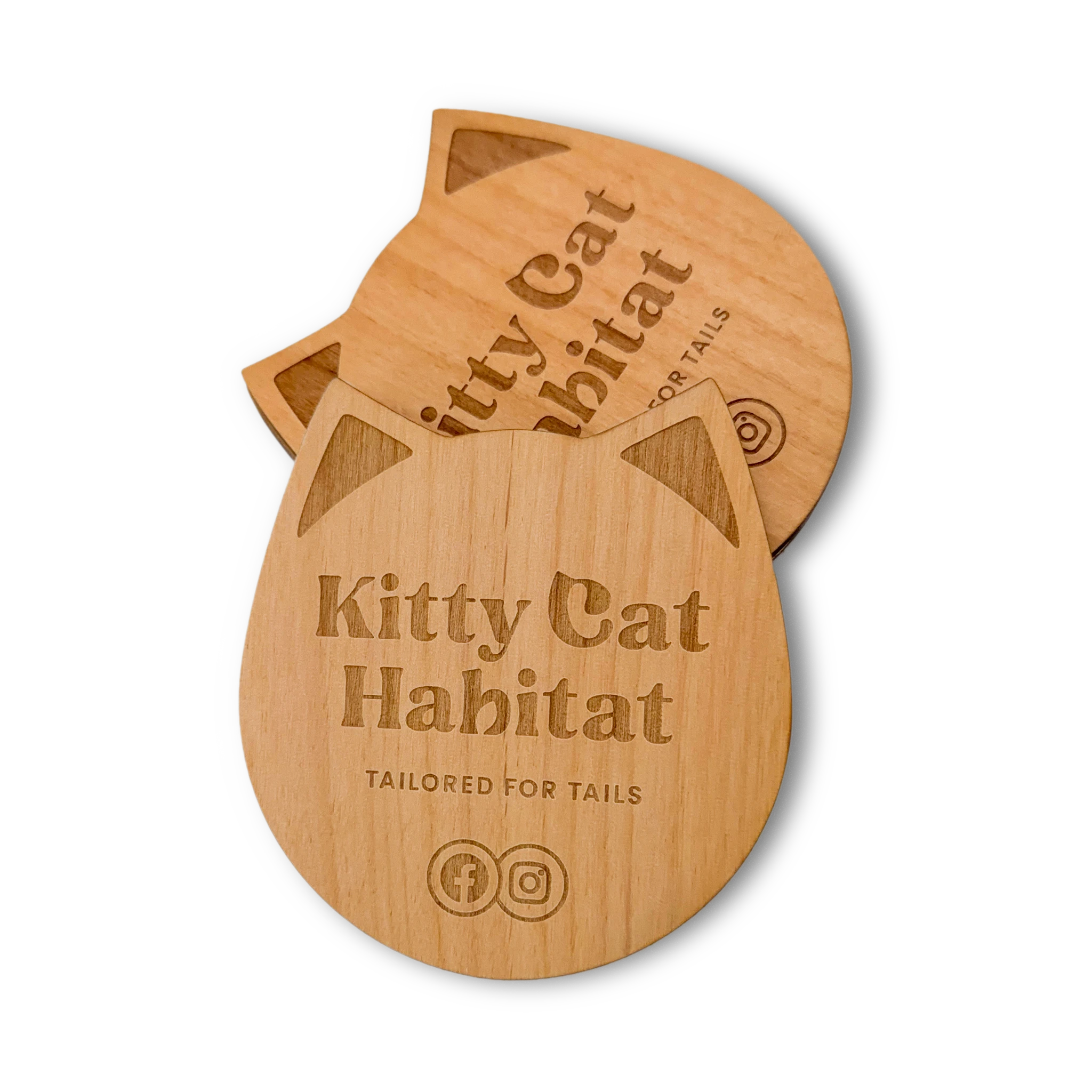 Stack of wooden cat head drink coasters showing the engraved logo on a light background.