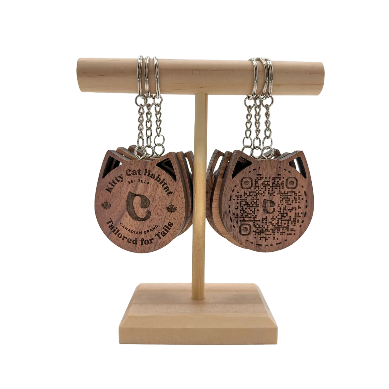 Walnut wooden cat head keychains on a wooden display stand showing both the logo side and QR code side on a light background.